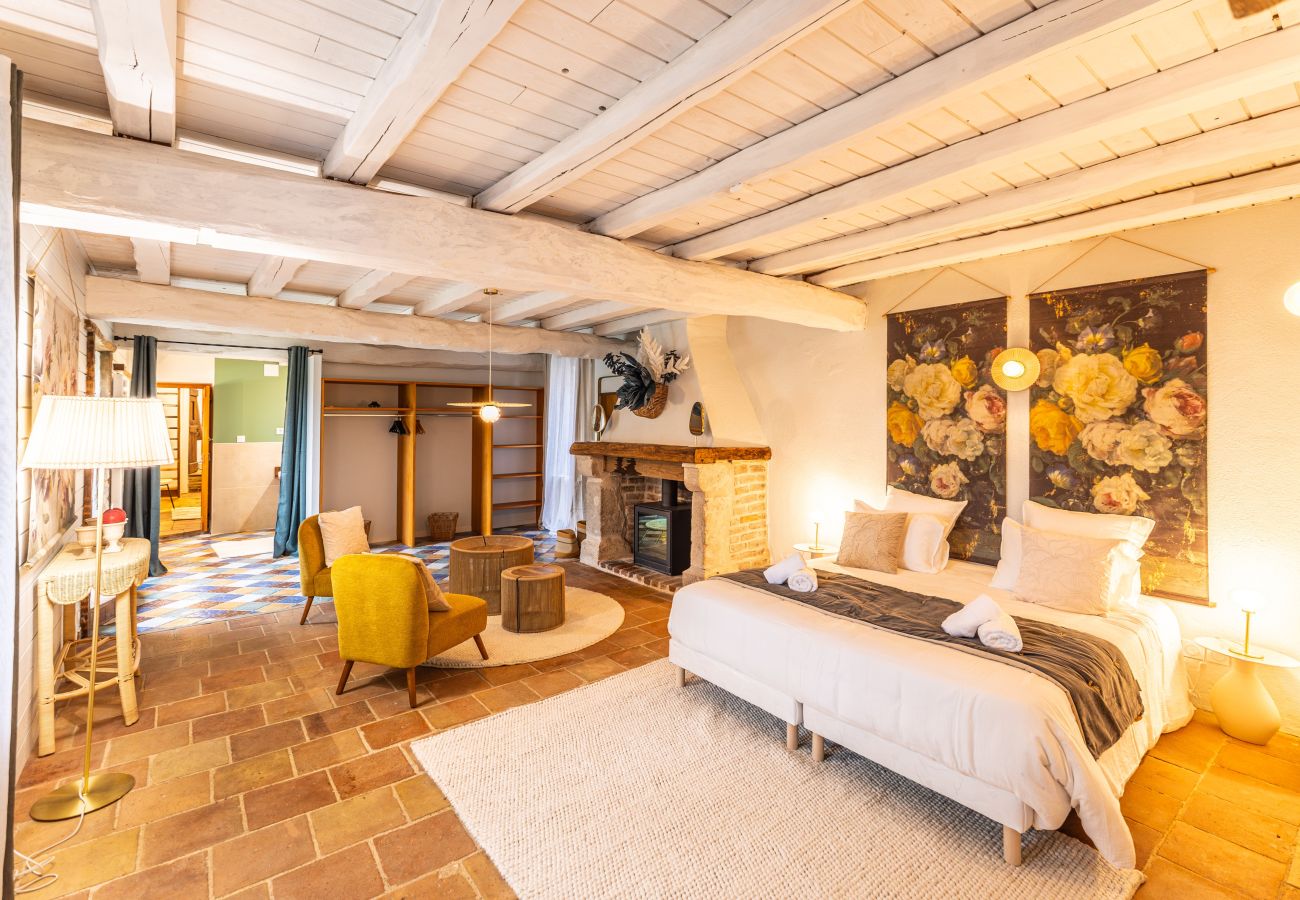 Bedroom with king-size bed, small lounge with armchair and wood-burning insert, dressing room and private bathroom.